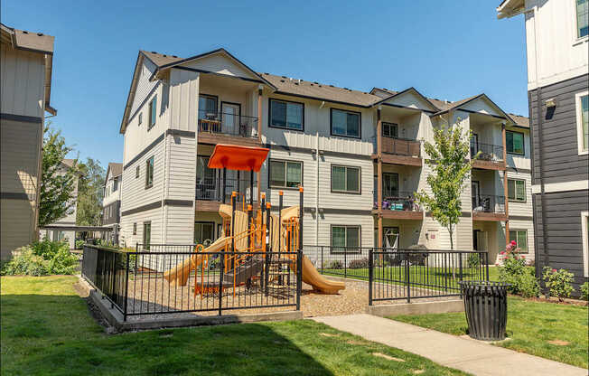 A playground with a slide is in front of a building at Forestplace Apartment Homes, Oregon
