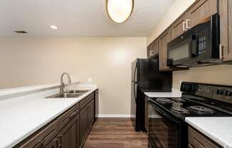 a kitchen with black appliances and white counter tops and wood floors