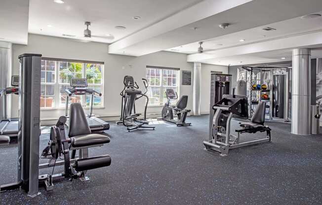 a gym with weights and cardio equipment on the floor and a window