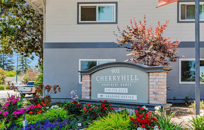 A sign for Cherryhill Apartments is in front of a building.
