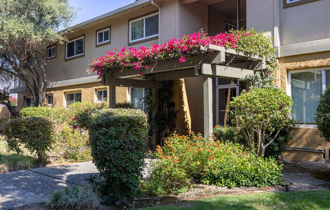 the front entrance of an apartment building with pink flowers on a porch