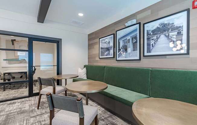 a lounge area with a green couch and tables and chairs