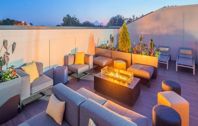 A modern outdoor seating area with a lit fire pit in the center.