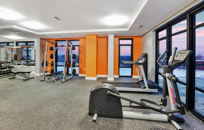 a gym with exercise equipment and windows with a view of the water