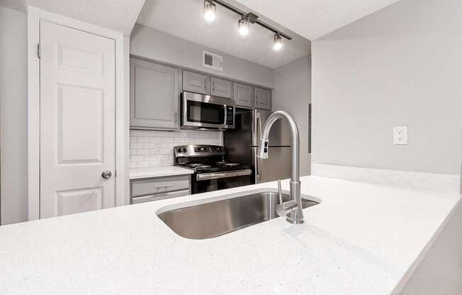 A2 upgraded apartment kitchen with a stainless steel sink and white countertop at Vine Apartments in Arlington, TX