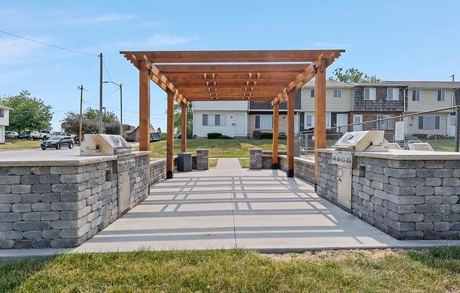 a stone walkway with a wooden pergola