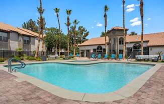 A swimming pool surrounded by palm trees and a building in the background.