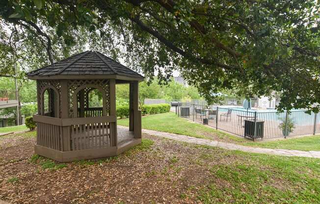 a gazebo in a park next to a pool