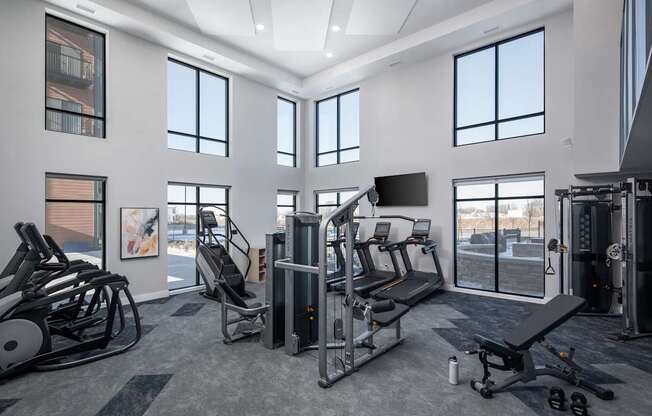 A gym with a variety of equipment including treadmills, weights, and exercise machines.