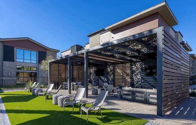 A modern house with a patio and lawn chairs.