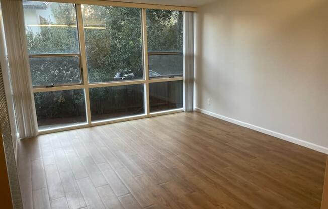 an empty living room with wood floors and a large window