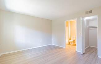 an empty living room with wood flooring and a toilet