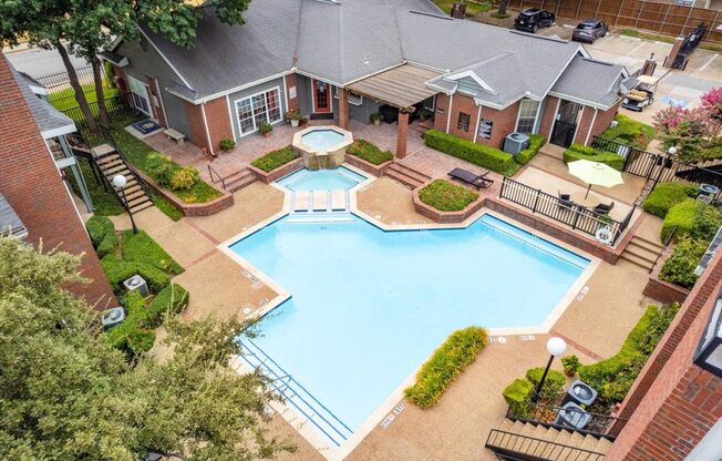 an aerial view of a large swimming pool with a house in the background