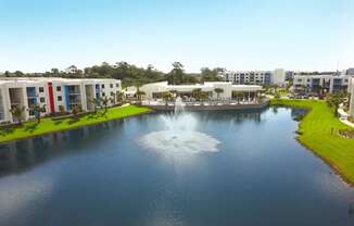 a fountain in the middle of a pond with buildings in the background at Icon One, Daytona Beach, FL