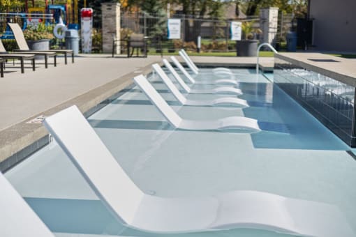 a row of white pool chairs in a pool