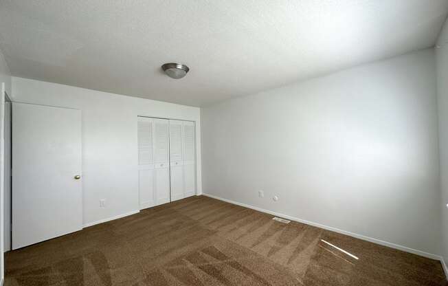 a bedroom with white walls and a brown carpet