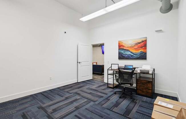 A business center with a carpeted floor and a painting on the wall.