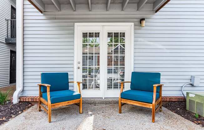 two blue chairs sitting in front of a white house