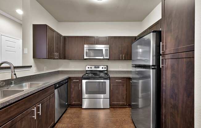 a kitchen with stainless steel appliances and dark wood cabinets