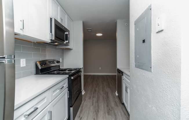 an empty kitchen with white cabinets and a black stove