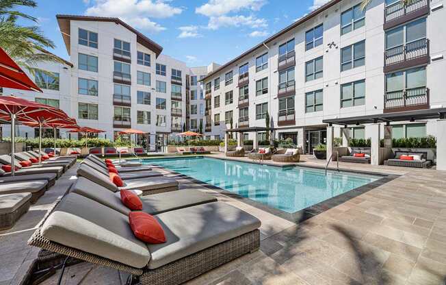 Resort-inspired pool deck with cushioned loungers, red umbrellas, and sparkling water perfect for relaxing weekends