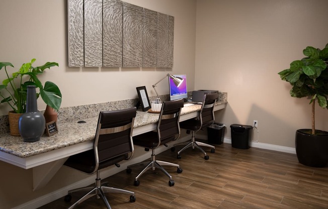 A room with a desk, chairs, and a computer monitor.