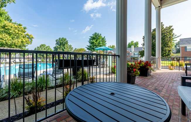 outdoor furniture on the porch of Littlestone Apartments clubhouse with a view of the pool