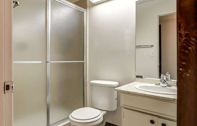 A white toilet sits in a bathroom next to a sink.