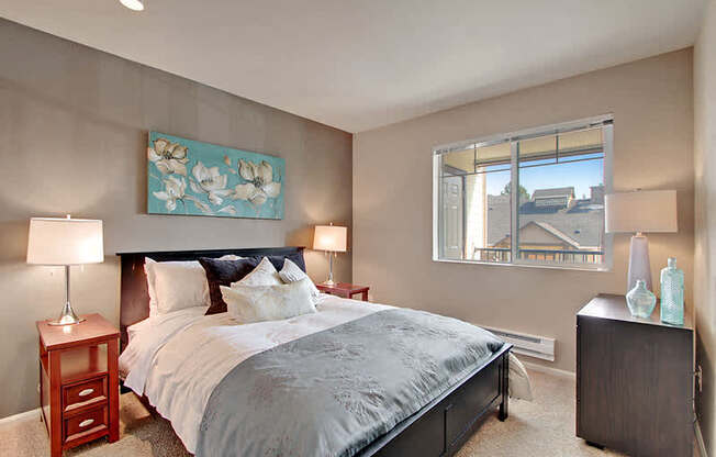 A bedroom with a large bed and a painting on the wall. at Mill Creek Meadows Apartments, Washington