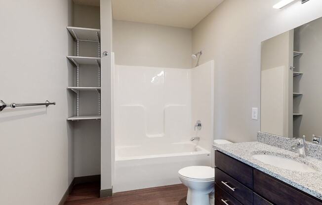 Bathroom with dual sink counter tops, a bathtub, and shelves for additional storage at Haven at Uptown in Lincoln, NE