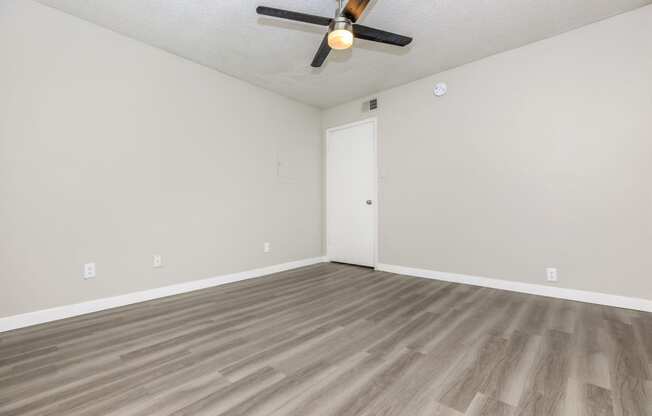 an empty bedroom with a ceiling fan and hardwood floors