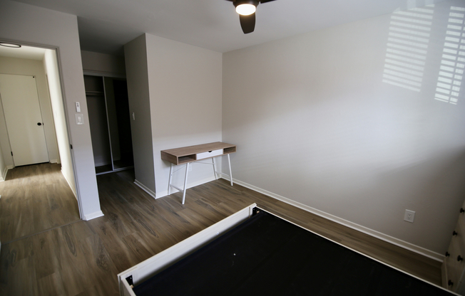 Bright and inviting bedroom with sleek wood flooring, a modern desk, and ample closet space, perfect for a functional and stylish living space.
