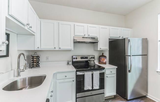 a white kitchen with stainless steel appliances and white cabinets