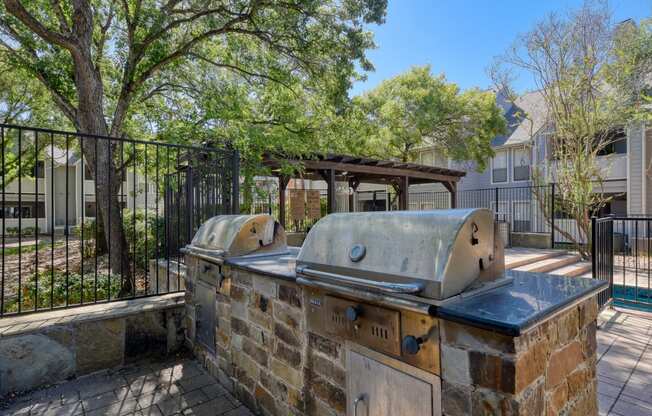 an outdoor kitchen with a grill and trees in the background