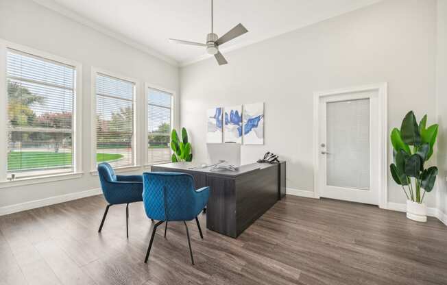 an office with a desk and chairs and a ceiling fan