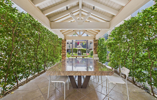 A table surrounded by chairs in a greenhouse.
