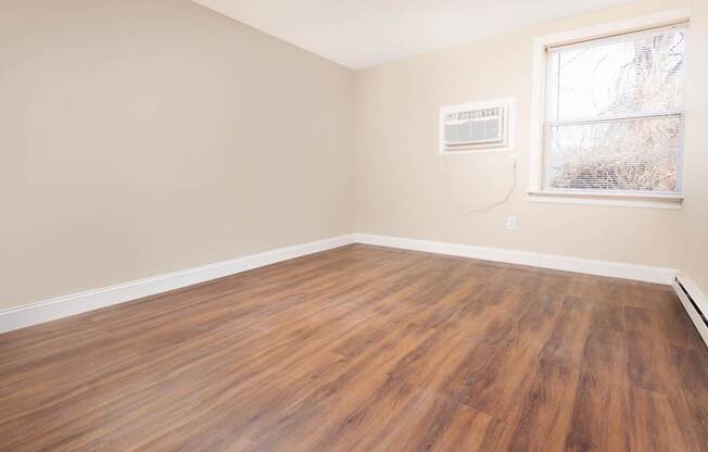 Empty room with wooden flooring and a window.