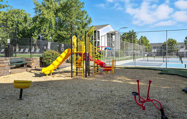 A playground with a yellow slide and red bike.