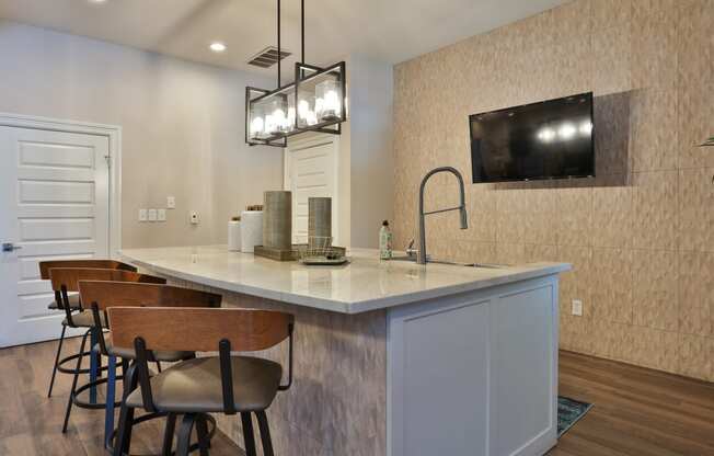 a kitchen with a large island with stools and a tv on the wall
