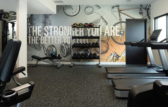 a gym with cardio equipment and a wall mural of the strength you are better you