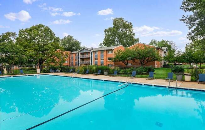 A large swimming pool in front of a building surrounded by trees.