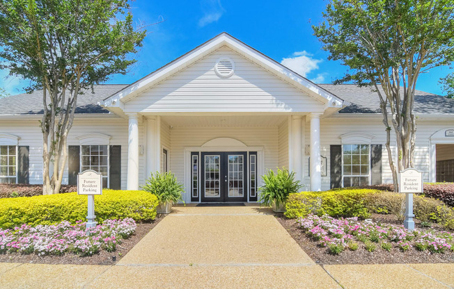 the front of a white house with a walkway and flowers in front of it at Reserve of Jackson Apartment Homes, Mississippi
