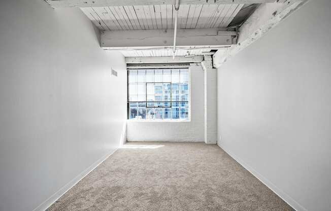 A large empty room with a window overlooking a cityscape.