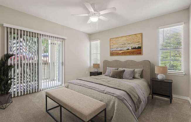 A bedroom with a large bed, a bench, and a ceiling fan.