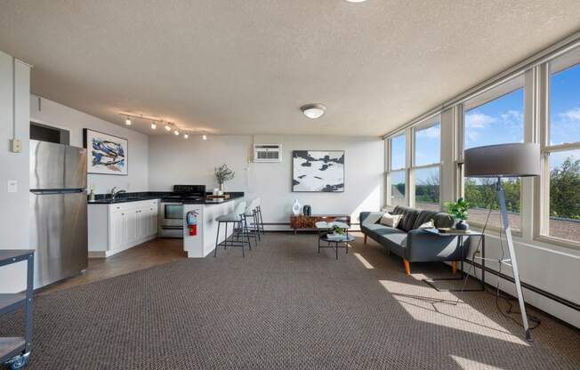 a living room with a couch and a kitchen with a large window