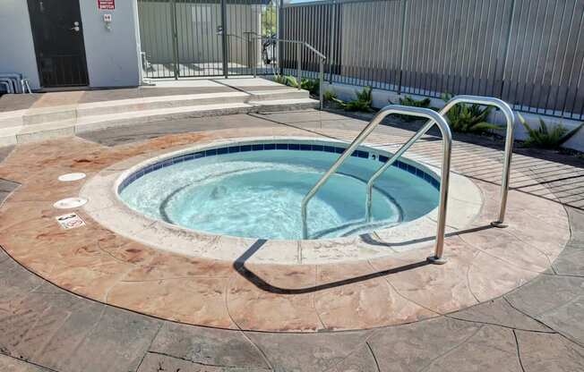 A hot tub sits inside the gated pool