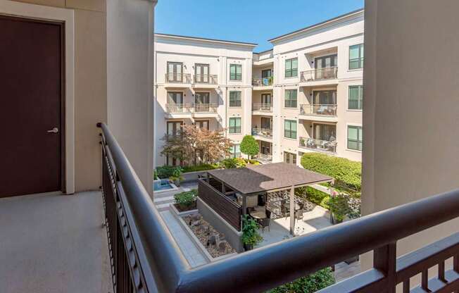 A balcony overlooks a courtyard with a building in the background.