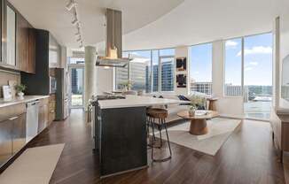 A modern kitchen with dark wood floors and stainless steel appliances.