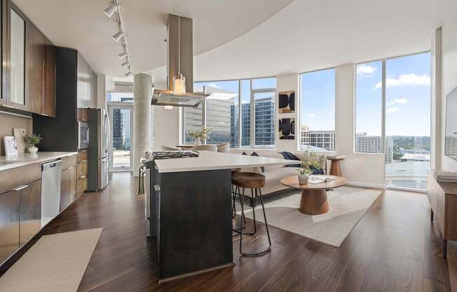 A modern kitchen with dark wood floors and stainless steel appliances.