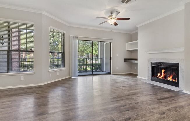 Pet Friendly Apartments in Plano, TX - Carrington Park Apartments Living Room With Fireplace, Ceiling Fan, Hardwood Style Flooring and Access to Outside Patio With Sliding Glass Door